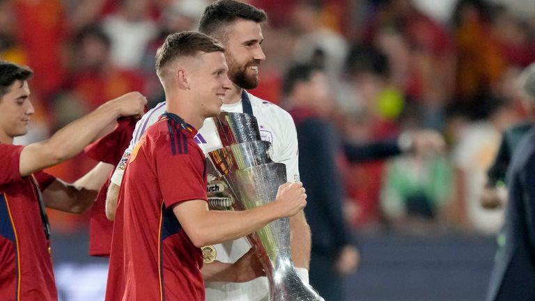 Spain's Dani Olmo and goalkeeper Unai Simon, right, pose with the trophy after winning the Nations League final soccer match between Croatia and Spain at De Kuip stadium in Rotterdam, Netherlands, Sunday, June 18, 2023. Spain won 5-4 in a penalty shootout after the match ended tied 0-0. (AP Photo/Peter Dejong)