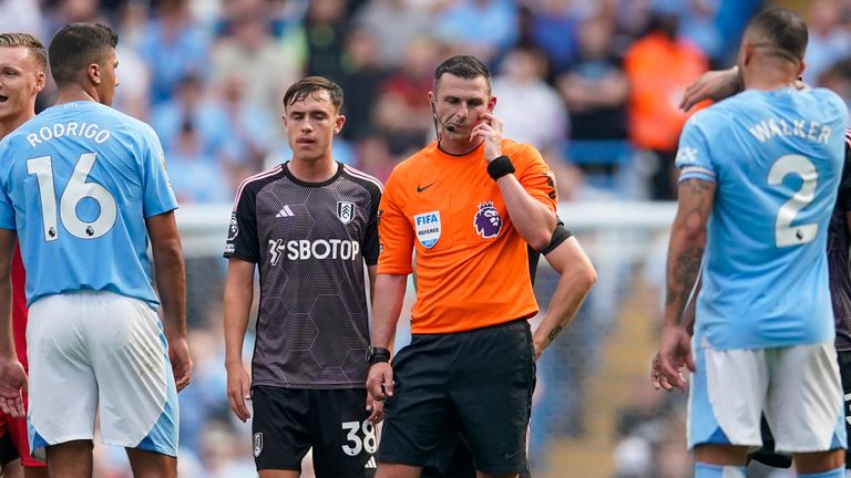 Referee Michael Oliver, centre, listens to VAR instructions from Stockley Park