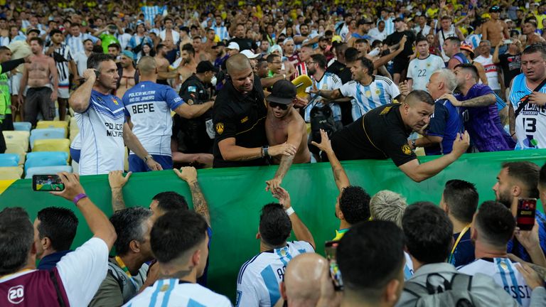 Players of Argentina try to calm the crowd after a fight between Brazilian and Argentinian fans broke out in the stands prior to a qualifying soccer match for the FIFA World Cup 2026 at Maracana stadium in Rio de Janeiro, Brazil, Tuesday, Nov. 21, 2023. (AP Photo/Silvia Izquierdo)