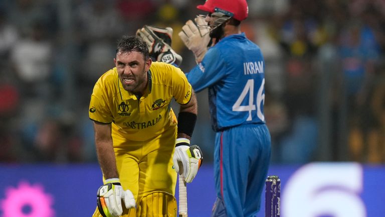 Australia's Glenn Maxwell, left, reacts in pain due to cramps during the ICC Men's Cricket World Cup match between Australia and Afghanistan