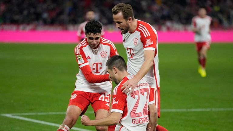 Bayern's Raphael Guerreiro, bottom, celebrates with his teammate Harry Kane