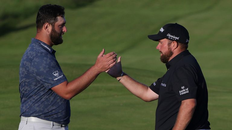 Spain's Jon Rahm, centre, bumps fists with Ireland's Shane Lowry, right as South Africa's Louis Oosthuizen looks on as they complete their second round of the British Open Golf Championship at Royal St George's golf course Sandwich, England, Friday, July 16, 2021. (AP Photo/Ian Walton)