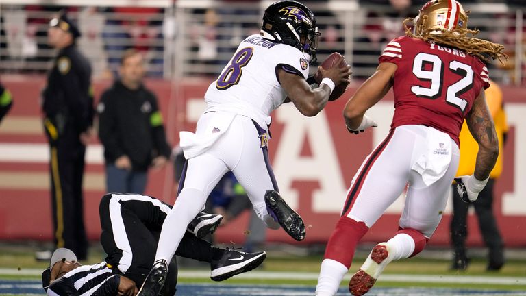 Umpire Alex Moore, bottom left, falls as Baltimore Ravens quarterback Lamar Jackson (8) runs from San Francisco 49ers defensive end Chase Young (92) during the first half