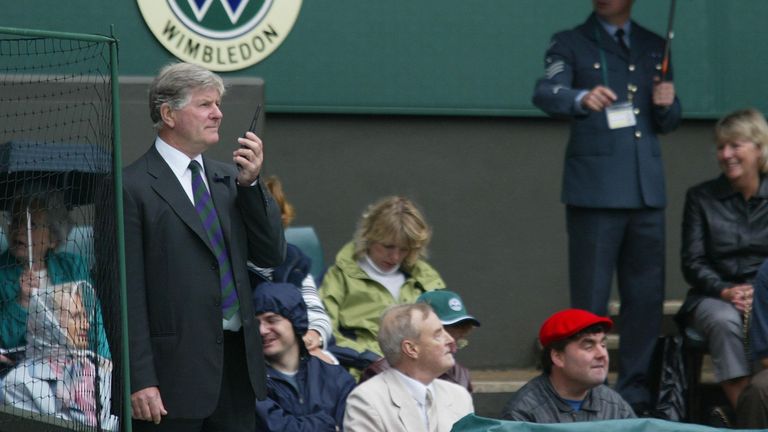 El árbitro de tenis de Wimbledon, Alan Mills (izquierda), comprueba el tiempo antes de ordenar al personal de tierra que cubra la cancha central hoy. Las cubiertas fueron retiradas y colocadas varias veces entre lluvias.