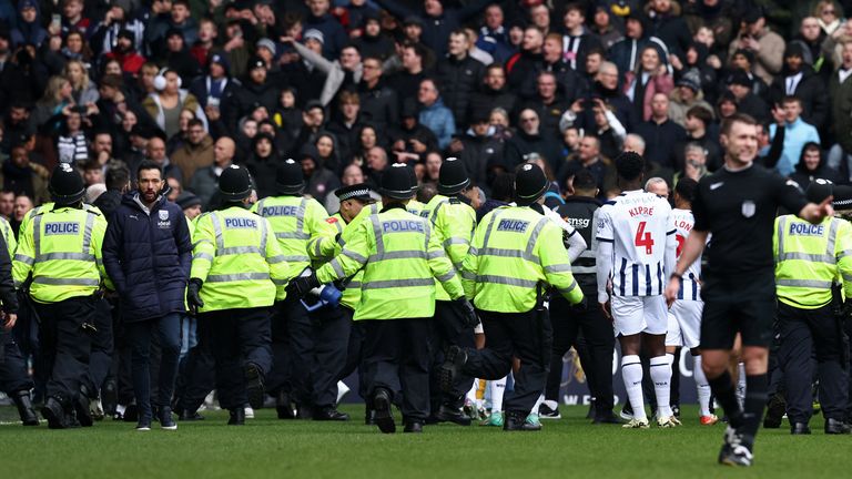 West Bromwich Albion manager Carlos Corberan walks across the pitch as police officers respond to crowd trouble in one corner of the stand at The Hawthorns