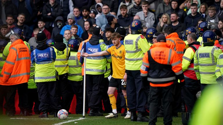 Wolves' Tommy Doyle attempts to take a corner while surrounded by police officers and stewards