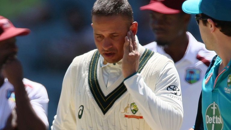 Australia's Usman Khawaja, third right, is escorted off the field after he was struck by a delivery from West Indies' Shamar Joseph on the third day of their cricket test match in Adelaide, Australia, Friday, Jan. 19, 2024. (AP Photo/James Elsby)