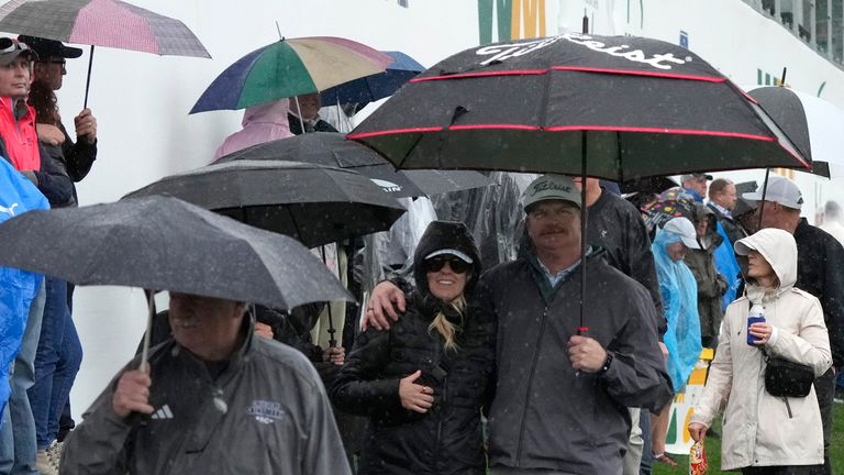 Fans in the gallery leave the ninth hole as rain pours down during the first round of the Phoenix Open golf tournament Thursday, Feb. 8, 2024, in Scottsdale, Ariz. (AP Photo/Ross D. Franklin)