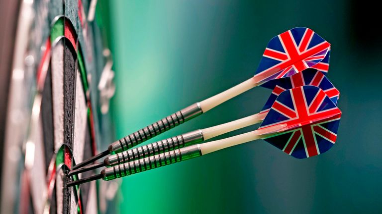 Three darts, with British union flag feathers, stick into the dart board as play continues in the quarterfinals of the World Darts Championship at Alexandra Palace in London, Monday, Jan. 1, 2024. (AP Photo/Kin Cheung)