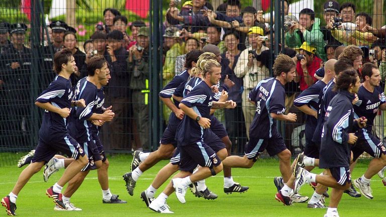 Players of Real Madrid run past a group of fans behind a fence during a training session at Hongta Sports Center Tuesday July 29, 2003 in Kunming, southwest China. The players of Real Madrid including Beckham continue training sessions through July 31 as part of their Asia Tour. 