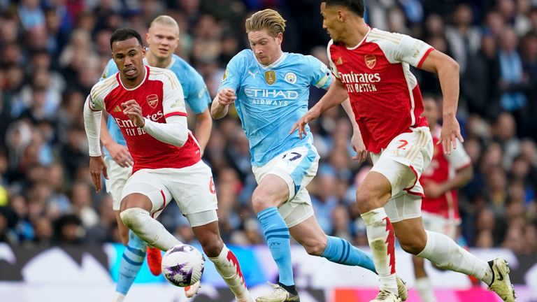 Manchester City's Kevin De Bruyne duels for the ball with Arsenal's Gabriel and William Saliba