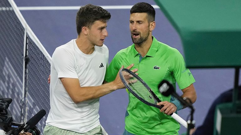 Luca Nardi talks with Novak Djokovic at the net after his upset win over the Serbian