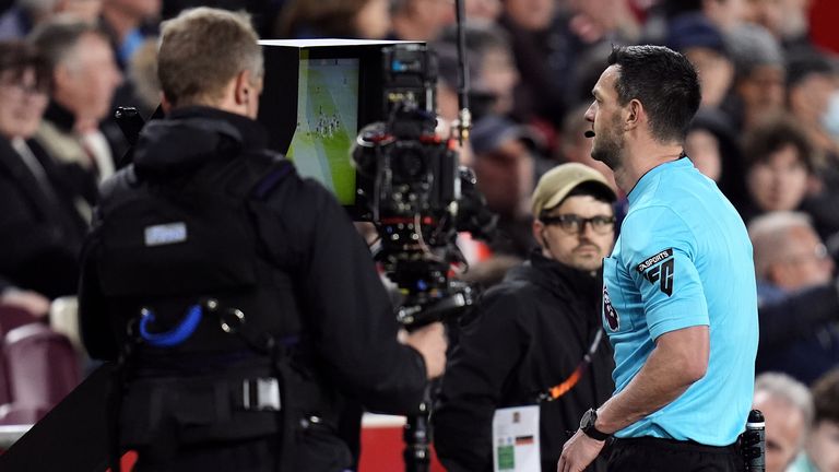 Referee Andrew Madley checks the pitch side VAR monitor for a potential penalty