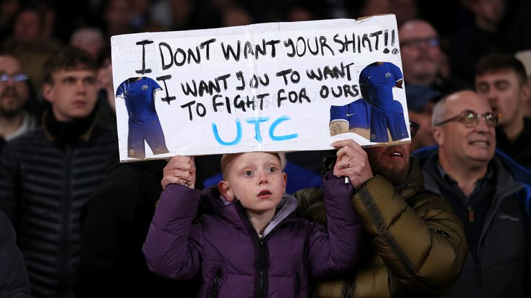 A young Chelsea fan holds up a sign reading 'I don't want your shirt!! I want you to want to fight for ours' during the Premier League match against Arsenal at the Emirates Stadium