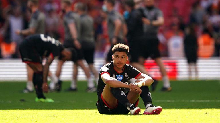 Lincoln City's Morgan Rogers appears dejected as Blackpool players and staff celebrate after the final whistle during the Sky Bet League One playoff final match at Wembley Stadium, London.  Picture date: Sunday May 30, 2021.