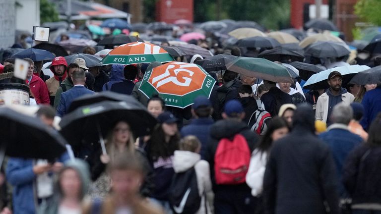 People walk under umbrellas during the French Open tennis tournament at the Roland Garros stadium in Paris, Wednesday, May 29, 2024. (AP Photo/Christophe Ena) 