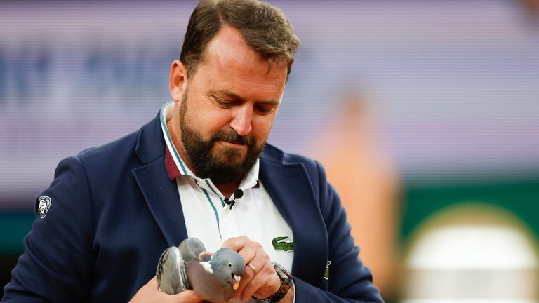 Chair umpire Damien Dumusois of France catches a pigeon that crashed onto the court during the third round match of the French Open tennis tournament between Tomas Machac of the Czech Republic and Russia's Daniil Medvedev at the Roland Garros stadium in Paris, Saturday, June 1, 2024. (AP Photo/Jean-Francois Badias)