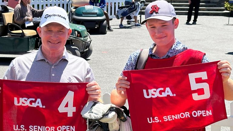 Frank Bensel, left, and his caddie and 14-year-old son, Hagen, pose with hole 4 and 5 flags after Bensel turned up a pair of aces on the back-to-back holes during the second round of the U.S. Senior Open golf tournament in Newport, R.I., Friday, June 28, 2024. (AP Photo/Jimmy Golen)