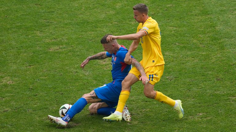 Slovakia's Juraj Kucka, left, is challenged by..Romania's Nicusor Bancu during a Group E match at the Euro 2024 soccer tournament in Frankfurt, Germany, Wednesday, June 26, 2024. (AP Photo/Darko Vojinovic)