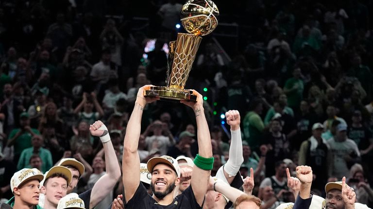 Boston Celtics forward Jayson Tatum holds, center, up the Larry O'Brien Championship Trophy as he celebrates with the team after they won the NBA basketball championship with a Game 5 victory over the Dallas Mavericks, Monday, June 17, 2024, in Boston. (AP Photo/Charles Krupa)