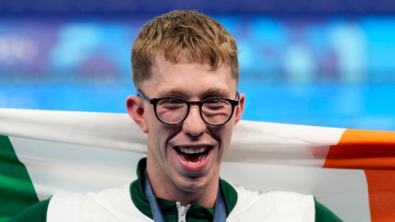 Gold medalist Daniel Wiffen, of Ireland, poses for a photo with his national flag on the podium following the men's 800-meter freestyle final at the 2024 Summer Olympics, Tuesday, July 30, 2024, in Nanterre, France. (AP Photo/Ashley Landis)