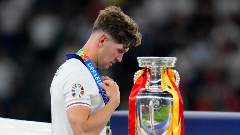 England's John Stones walks past the trophy