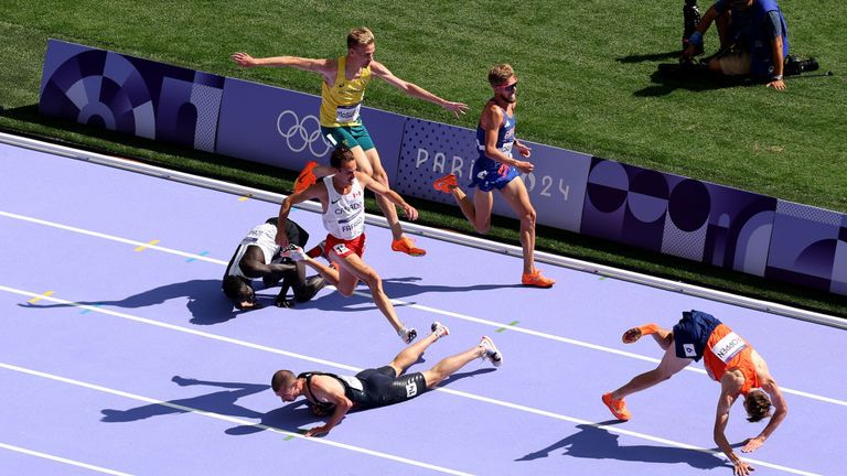 Dominic Lokinyomo Lobalu of Refugee Olympic Team and George Mills of Team Great Britain (R) fall on the ground during the Men's 5000m 