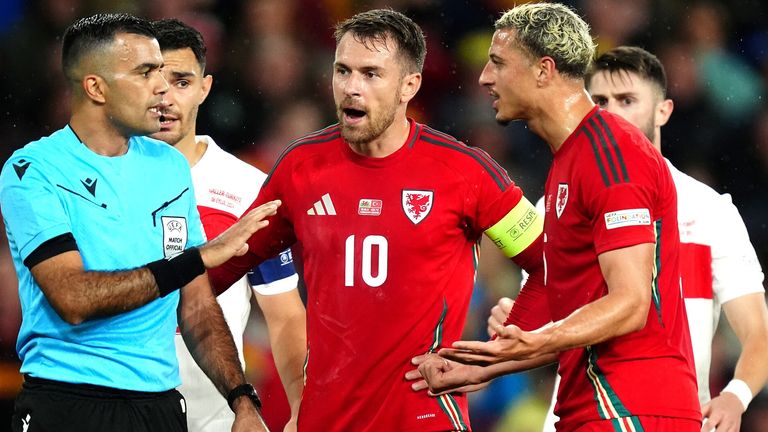 Referee Rohit Saggi speaks to Wales' Aaron Ramsey and Ethan Ampadu 