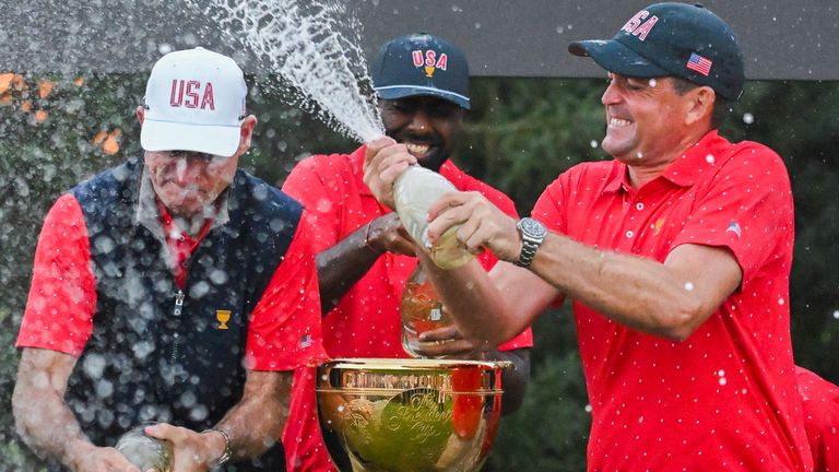 Teamlid Keegan Bradley uit de Verenigde Staten, rechts, spuit kapitein Jim Furyk, midden en teamgenoten met champagne na het winnen van de Presidents Cup over het internationale team op de Royal Montreal Golf Club in Montreal, zondag 29 september 2024. (Graham Hughes / De Canadese pers via AP) 