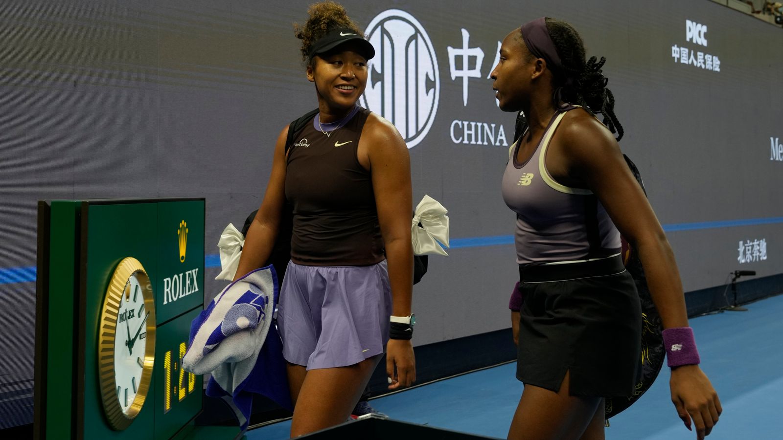 Coco Gauff carries Naomi Osaka’s bags off court after the Japanese star retired injured from their match in Beijing