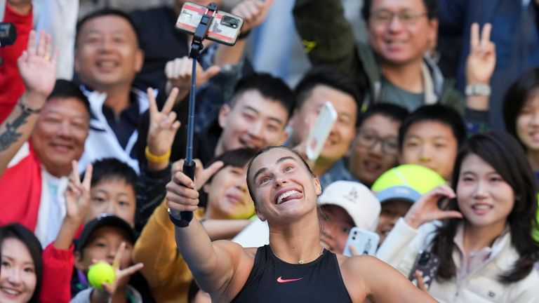 Aryna Sabalenka of Belarus takes a selfie with fans after winning against Madison Keys of the United States during their women's singles match of the China Open tennis tournament, at the National Tennis Center in Beijing, Wednesday, Oct. 2, 2024. (AP Photo/Achmad Ibrahim)