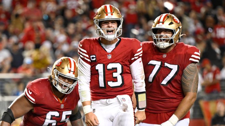 San Francisco 49ers quarterback Brock Purdy (13) with linebackers Aaron Banks (left) and linebackers Aaron Banks (left) during the second half of an NFL football game against the Dallas Cowboys on Sunday in Santa Clara, California. Linebacker Dominic Puni (77) celebrates after a touchdown.