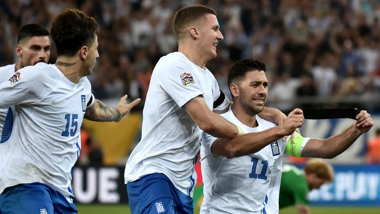 Tasos Bakasetas celebrates scoring his team's first goal by holding up the black armband in honour of the passing of former Greek football player George Baldock 