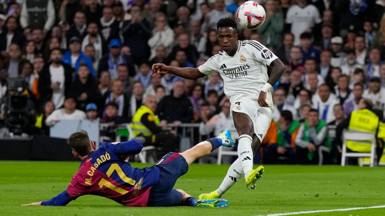 Real Madrid's Vinicius Junior is challenged by FC Barcelona's Marc Casado