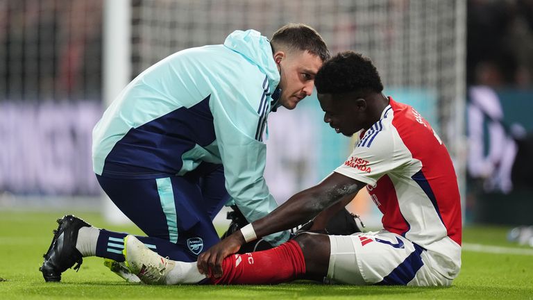 Arsenal's Bukayo Saka receives treatment from medical staff after going down injured