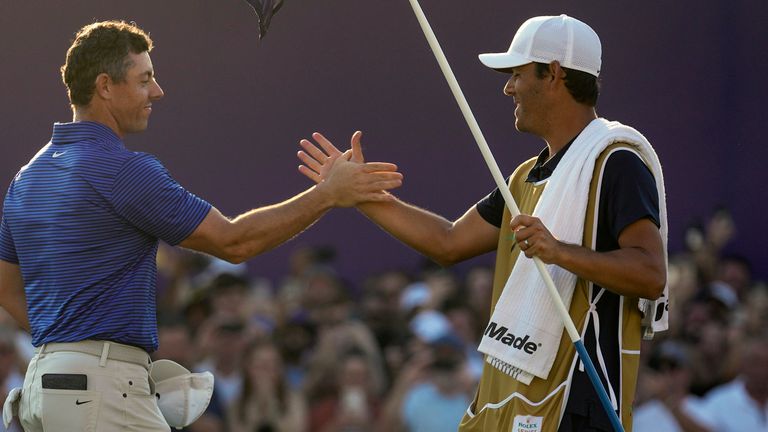 Rory McIlroy of Northern Ireland, left, celebrates with his caddie after winning the World Tour Golf Championship in Dubai, United Arab Emirates, Sunday, Nov. 17, 2024. (AP Photo/Altaf Qadri)