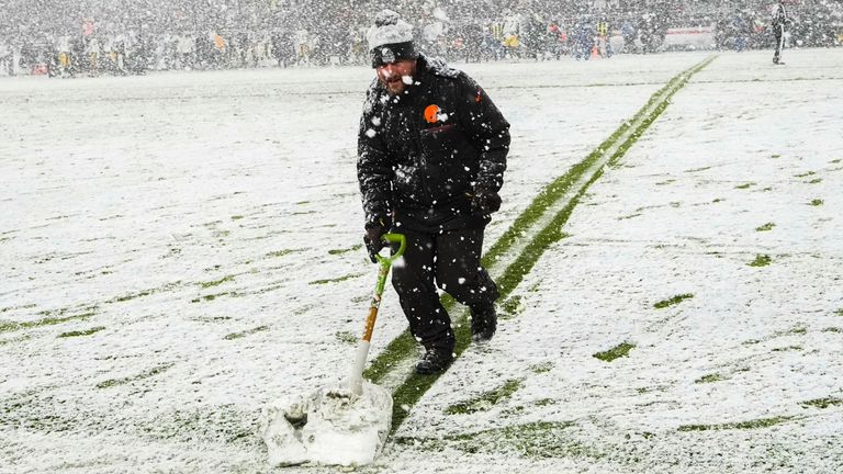 A groundskeeper shovels snow on the field in the second half of an NFL football game between the Cleveland Browns and the Pittsburgh Steelers, Thursday, Nov. 21, 2024, in Cleveland. (AP Photo/Sue Ogrocki)