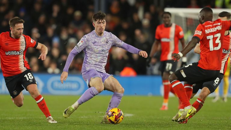 Josh Key of Swansea City (C) controls the ball under pressure from Jordan Clark (L) and Marvelous Nakamba (R) of Luton Town