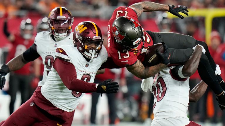 Penerima lebar Tampa Bay Buccaneers Mike Evans (13) dijegal melawan keselamatan Washington Commanders Quan Martin, kanan bawah, dan gelandang Dante Fowler Jr., kiri depan, selama paruh kedua pertandingan sepak bola playoff wild-card NFL di Tampa, Florida. , Minggu, 12 Januari 2025. (AP Photo/Chris O'Meara)