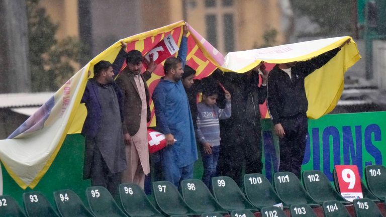 Fans stand under a sheet during rain as they wait for the start of the ICC Champions Trophy cricket match between Pakistan and Bangladesh, in Rawalpindi, Pakistan Thursday, Feb. 27, 2025. (AP Photo/Anjum Naveed)