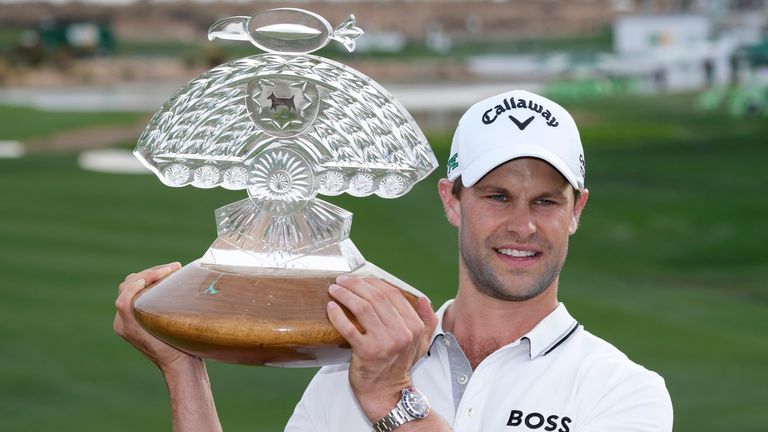 Thomas Detry, of Belgium, smiles as celebrates after his win at the Phoenix Open golf tournament at TPC Scottsdale while holding the winner's trophy and posing for photographers Sunday, Feb. 9, 2025, in Scottsdale, Ariz. (AP Photo/Ross D. Franklin)