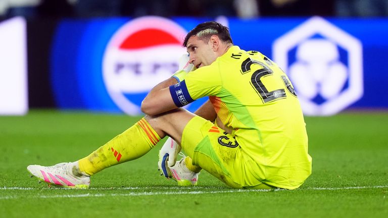 Emi Martinez sits dejected on the pitch after Aston Villa's exit from the Champions League