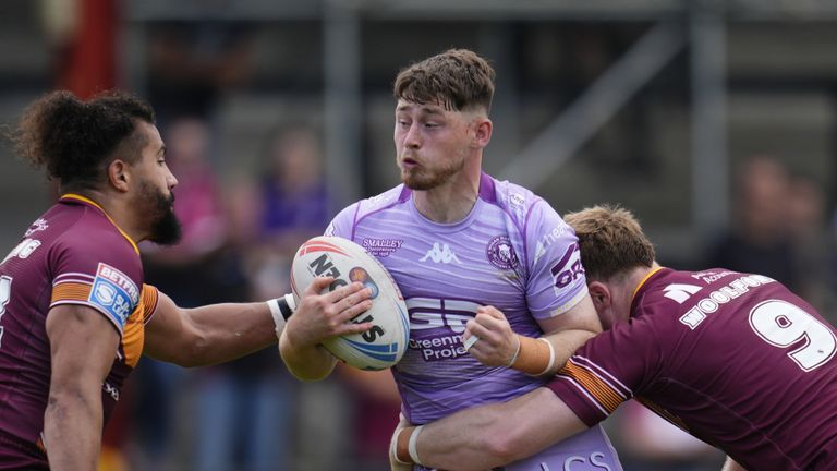 Jack Farrimond (Center) of Wigan Warriors is covered by Zac Woolford (right of the Giants de Huddersfield (right)