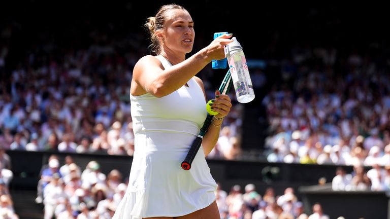 Aryna Sabalenka passes a water bottle and ice pack to a person in the crowd during her match against Amanda Anisimova on day eleven of the 2