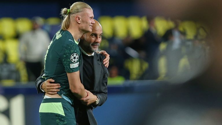 Manchester City's head coach Pep Guardiola leaves the field with Erling Haaland