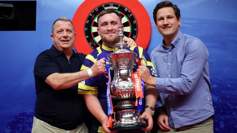 L'inglese Luke Littler posa con il Phil Taylor Trophy insieme a Garry Plummer, proprietario di Target Darts e James Tattersall, manager di Dire