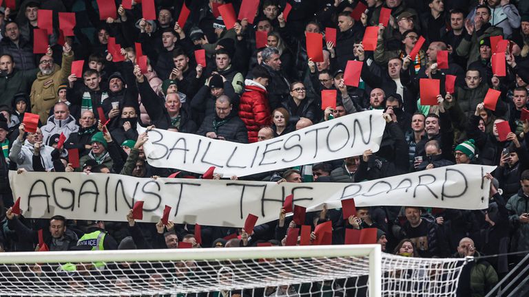 Torcedores do Celtic seguram uma faixa e cartões vermelhos contra o tabuleiro