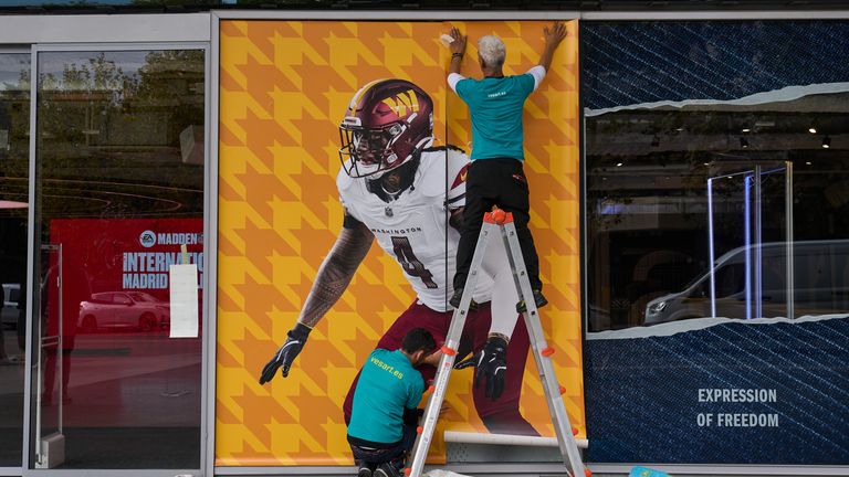 A worker pastes a poster on the facade of the renovated Santiago Bernabeu stadium ahead of Sunday's NFL game 