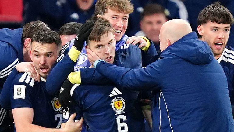 Kieran Tierney is mobbed by his Scotland team-mates after his stoppage-time goal set them on their way to victory over Denmark