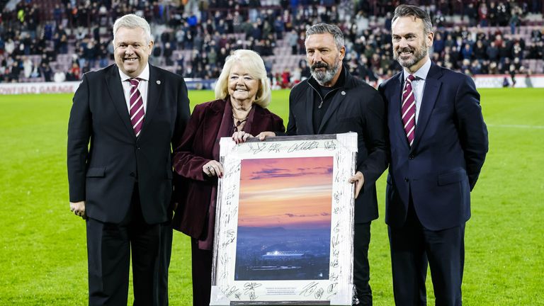 El director ejecutivo de Hearts, Andrew McKinlay (izquierda), el entrenador en jefe Derek McInnes y el presidente de la Fundación Hearts, Gerry Mallon (derecha), le entregaron un regalo a Budge.